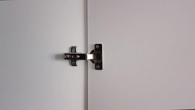 Metal hinges of the cabinet door close-up. Adjusting the hinges of cabinet doors and chiffoniers. Furniture accessories.
