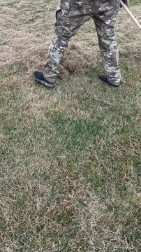  man clogs the felt with a lawn with red plastic rags, after aeration