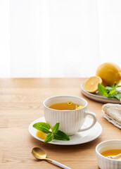 Cup of herbal tea with lemon, honey and mint on wooden tabletop
