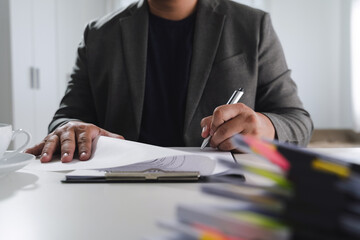 Pen signing a document person gray blazer is sitting desk, signing documents with pen, surrounded...