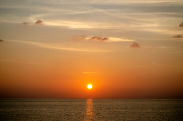 Stunning sunset over the Andaman Sea in Phuket, Thailand, with vibrant hues of orange, pink, and purple reflecting on the calm waters