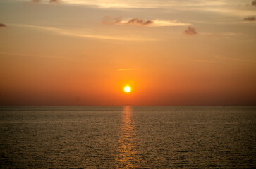 Stunning sunset over the Andaman Sea in Phuket, Thailand, with vibrant hues of orange, pink, and purple reflecting on the calm waters