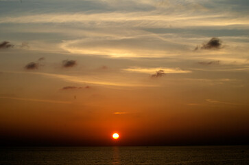 Stunning sunset over the Andaman Sea in Phuket, Thailand, with vibrant hues of orange, pink, and purple reflecting on the calm waters