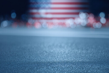 Blurred American flag with bokeh lights and asphalt foreground
