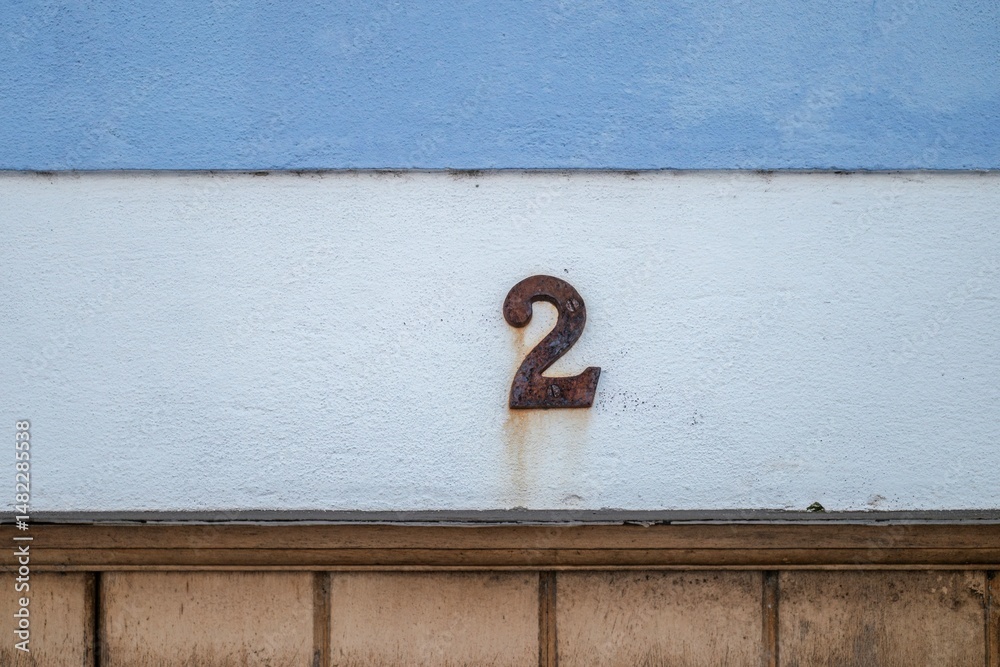 Fototapete rusty number two on textured wall. close-up of a weathered, rusty metal house number '2' affixed to 