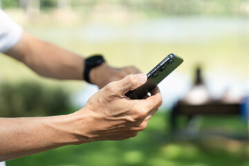 Wellness and Technology. Senior man using smartphone in park for health tracking.