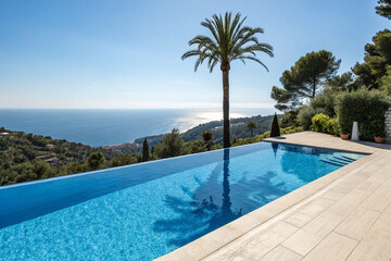 Beautiful blue fresh infinity swimming pool in a villa in sunny Spain with sea views. Has a shadow from a palm tree in the center of the pool.