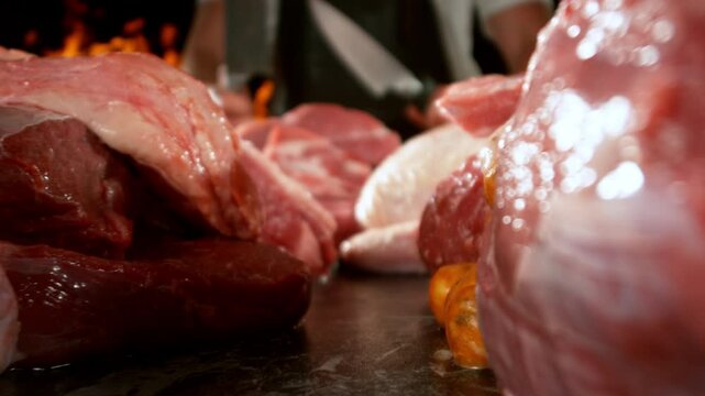 Slow motion, camera move. Large assortment of premium raw meat, beef, sausages, pork and chicken suitable for butchery advertising, fire on background