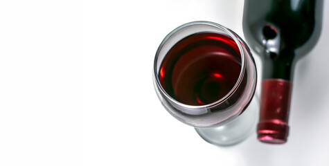 Glass and bottle of red wine close-up on white background.