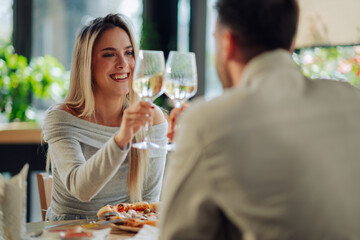 Happy couple toasting with white wine, enjoying romantic dinner at restaurant