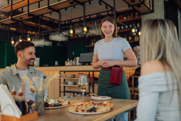Smiling waitress taking order from customers in pizzeria restaurant