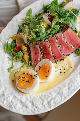 Fresh tuna salad with egg and greens on restaurant table