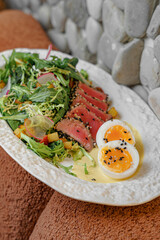 Fresh tuna salad with egg and greens on restaurant table
