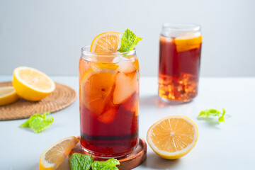 Iced tea with lemon and ice in a tall glass on a white background. The concept of a refreshing drink or lemonade on a hot summer day. Front view and copy space.