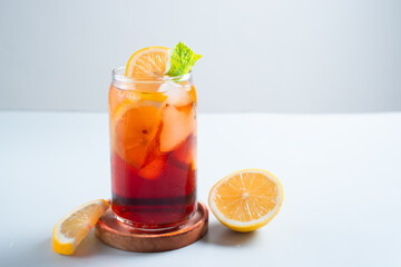 Iced tea with lemon and ice in a tall glass on a white background. The concept of a refreshing drink or lemonade on a hot summer day. Front view and copy space.