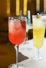 Closeup red and yellow cocktails in golden interior