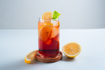 Iced tea with lemon and ice in a tall glass on a white background. The concept of a refreshing drink or lemonade on a hot summer day. Front view and copy space.