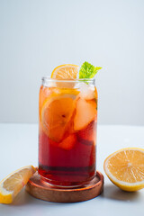 Iced tea with lemon and ice in a tall glass on a white background. The concept of a refreshing drink or lemonade on a hot summer day. Front view and copy space.