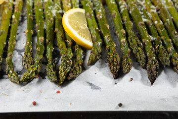Grilled asparagus with lemon on baking tray and cheese