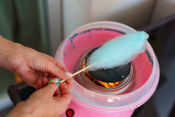 Woman making cotton candy at home using a small countertop cotton candy machine.