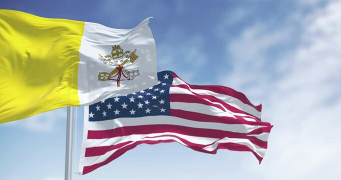 Vatican city flag waving in the wind with the American flag on a clear day