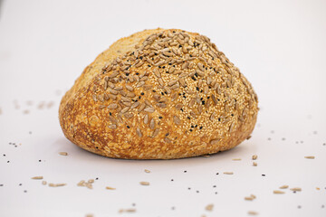 Whole artisan wheat bread with sesame and sunflower seeds on white background