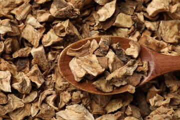 Pieces of dry chicory roots and spoon as background, closeup