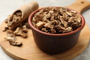 Pieces of dry chicory roots in bowl and scoop on gray table, closeup