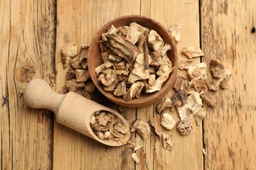 Pieces of dry chicory roots in bowl and scoop on wooden table, flat lay