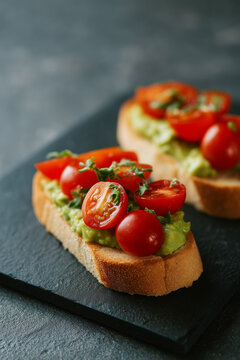 Bruschetti with tomato and avocado on grey minimal background. 