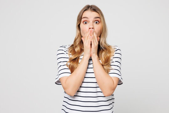Young happy shocked surprised Caucasian woman she wearing striped t-shirt casual clothes cover mouth with hand look camera isolated on plain solid white background studio portrait. Lifestyle concept.
