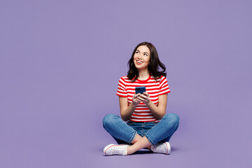 Full body young woman she wear red striped t-shirt casual clothes sit hold in hand use mobile cell...