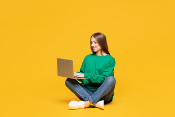 Full body young IT woman wearing green sweatshirt casual clothes sit hold use work on laptop pc...
