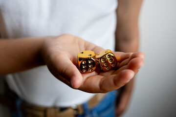Close up of young hispanic female holding two gold dice in hand