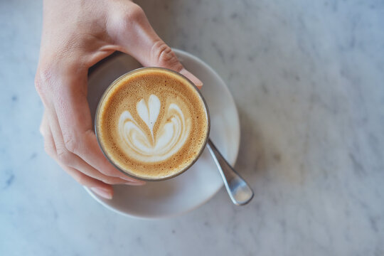 Hand holding a glass of coffee latte