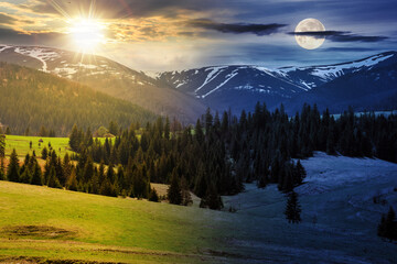 day and night time change concept. rural landscape with pasture and forest hill. snow capped mountains. nature scenery on spring equinox. cloudy sky with sun and moon