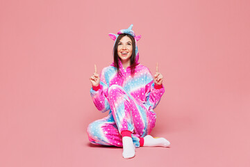 Full body young woman wears domestic costume with hoody and animal ears point index finger overhead on area mock up isolated on plain pastel light pink background studio portrait. Lifestyle concept.