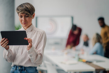 Businesswoman using digital tablet while coworkers are having a meeting