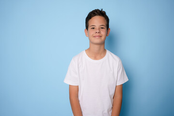 Obraz premium Child boy wearing white t-shirt standing isolated over light blue background.