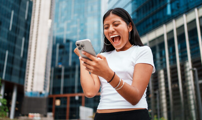 A Young Woman Engaged with Her Smartphone While Surrounded by a Vibrant, Energetic Urban Setting