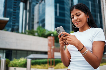 A young woman is using her smartphone while enjoying the urban city setting around her