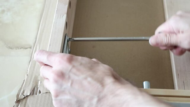 Close up of male hands using screwdriver to tighten screw