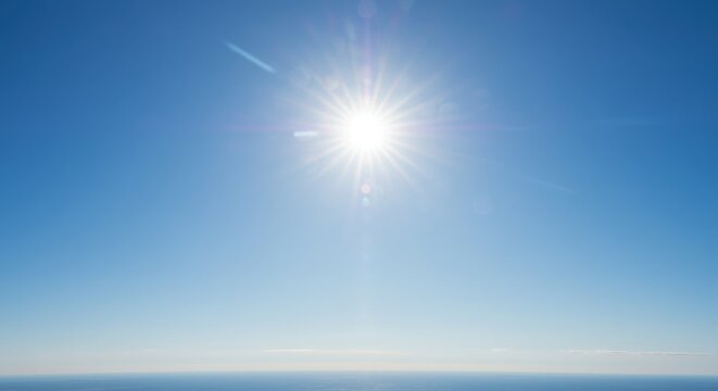 Bright sun shining over a clear blue sky above a tranquil ocean horizon
