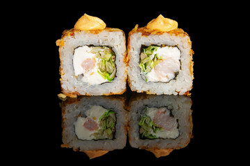 Deep-fried sushi rolls filled with shrimp, fresh lettuce and cream cheese, topped with spicy mayo. Isolated on black background with reflection, perfect for menus or ads