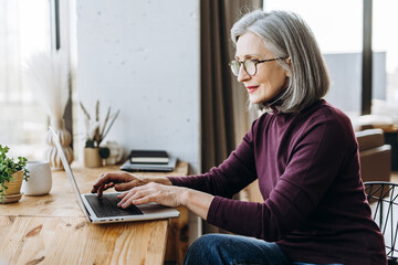 Senior freelancer working remotely from home office using laptop