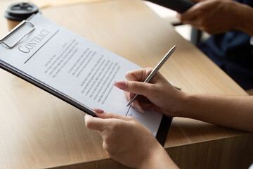 Business Contract Signing. Professional hands signing a contract on a wooden table.