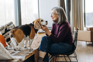 Senior woman bonding with beagle dog at home: expressing love and companionship