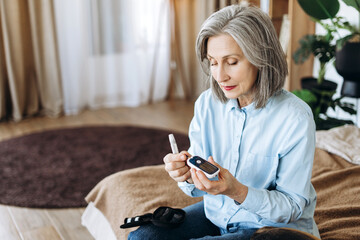 Senior woman checking blood sugar level at home