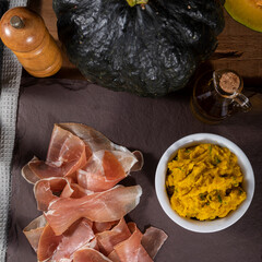 Italian prosciutto crudo or jamon with pumpkin mashed. Raw ham on wood