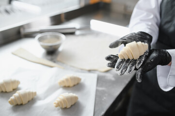 Baker showing freshly made croissant in bakery